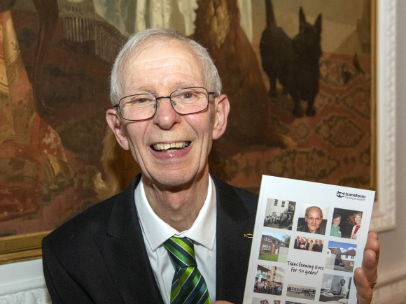 A photo of former Transform Chief Executive Paul Mitchell holding a copy of the Transform History which he wrote